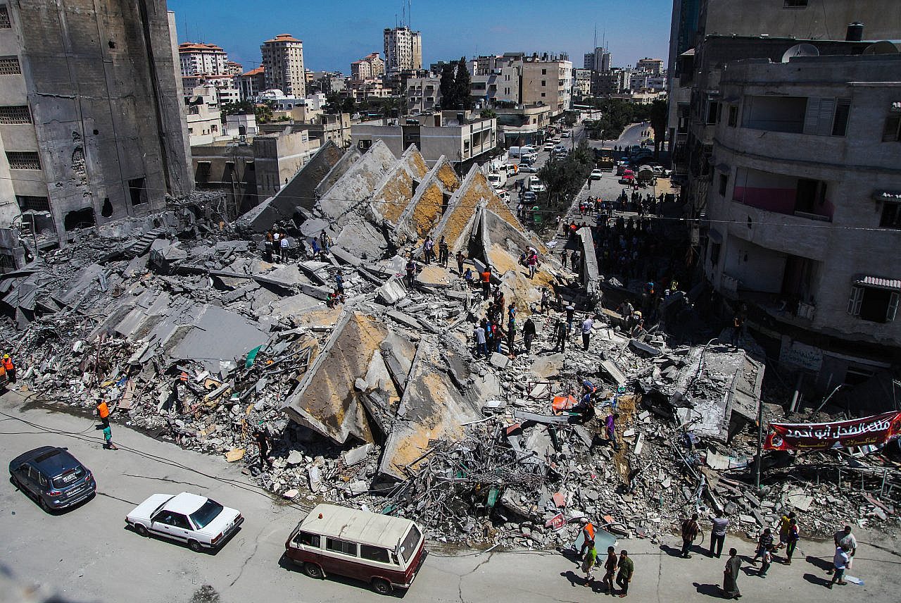 Des Palestiniens se rassemblent autour des restes d'une tour abritant des bureaux qui, selon des témoins, a été détruite par une frappe aérienne israélienne dans la ville de Gaza, le 26 août 2014. (Emad Nassar/Flash90)